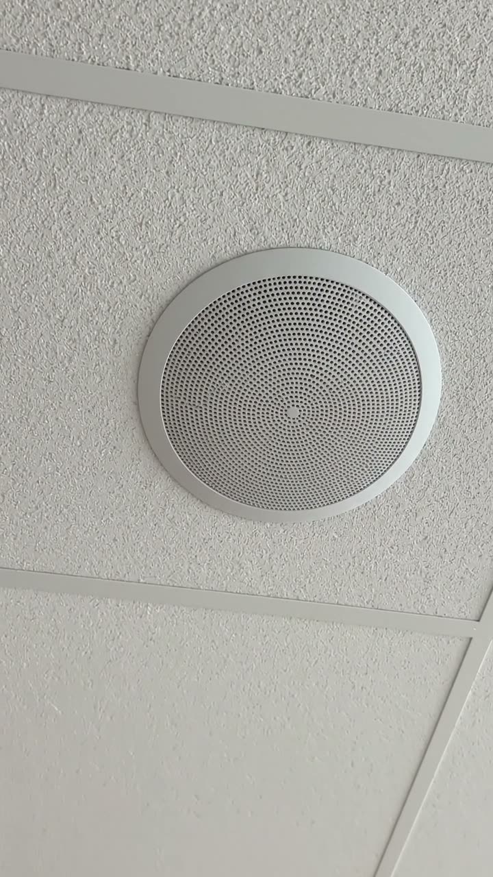 A ceiling speaker fitted flush in a suspended ceiling tile
