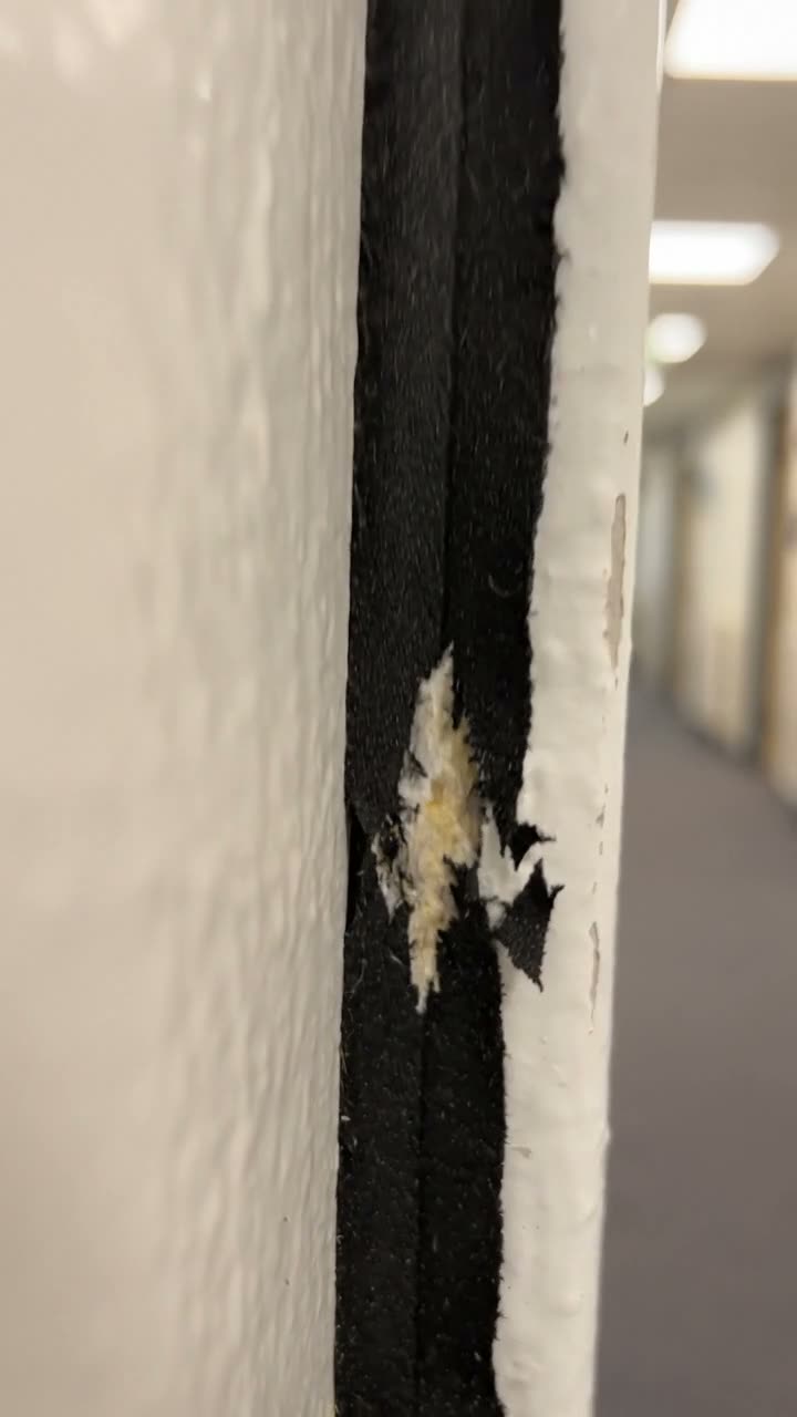 A torn intumescent strip on the edge of a fire door