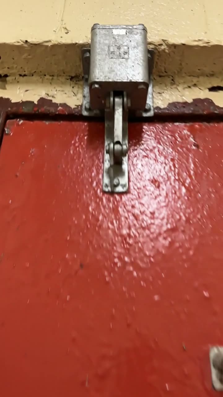 An overhead closer fixed above a red fire door