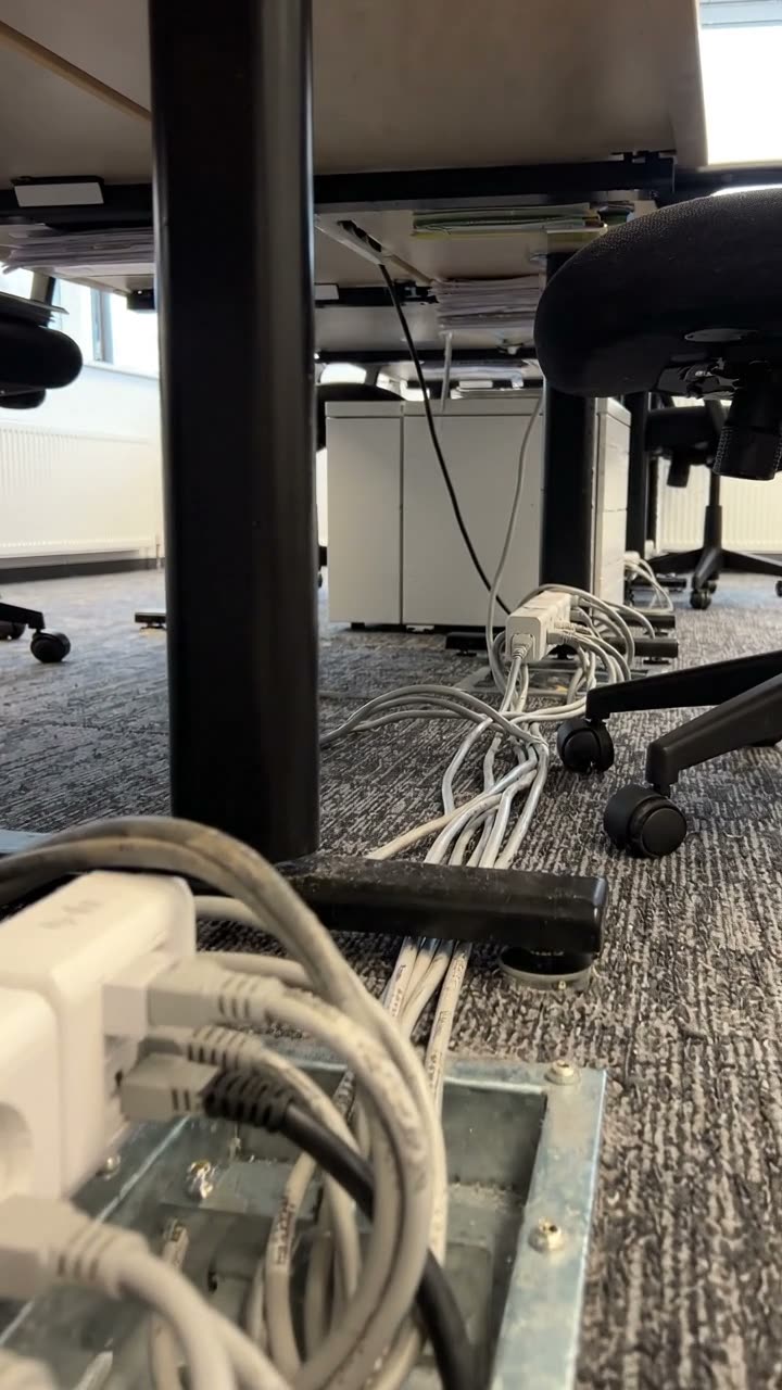 An open floor box under a desk with patch leads