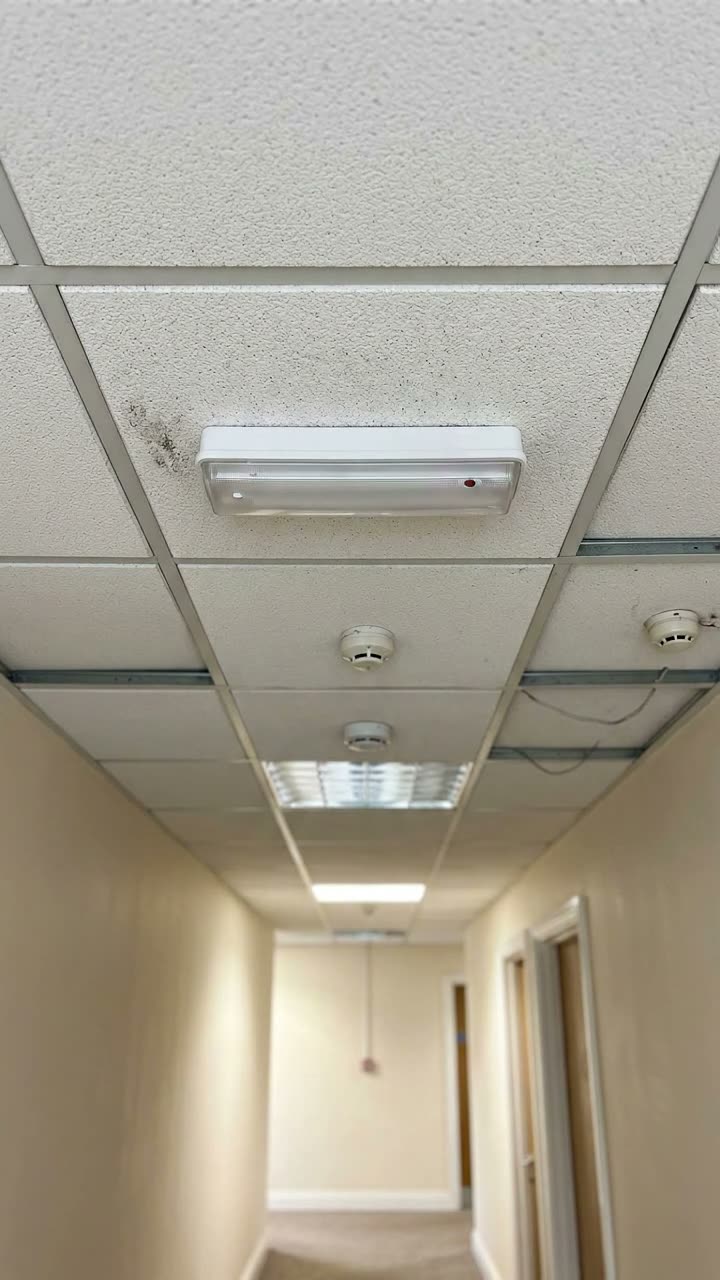 An emergency light fitting in a corridor ceiling