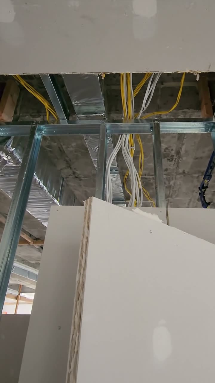 A plasterboard partition that stops short of the slab, with cables passing over it