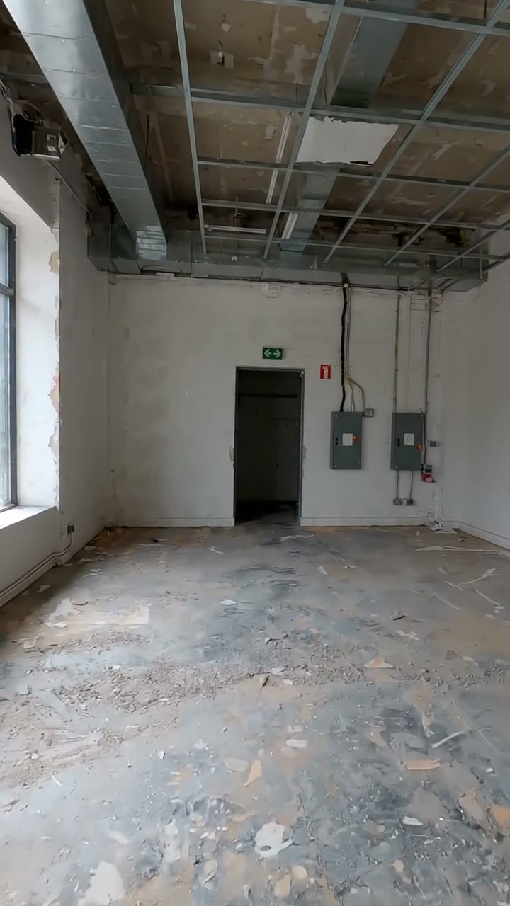 An empty retail unit seen from the entrance, with the rear door and distribution boards on the back wall