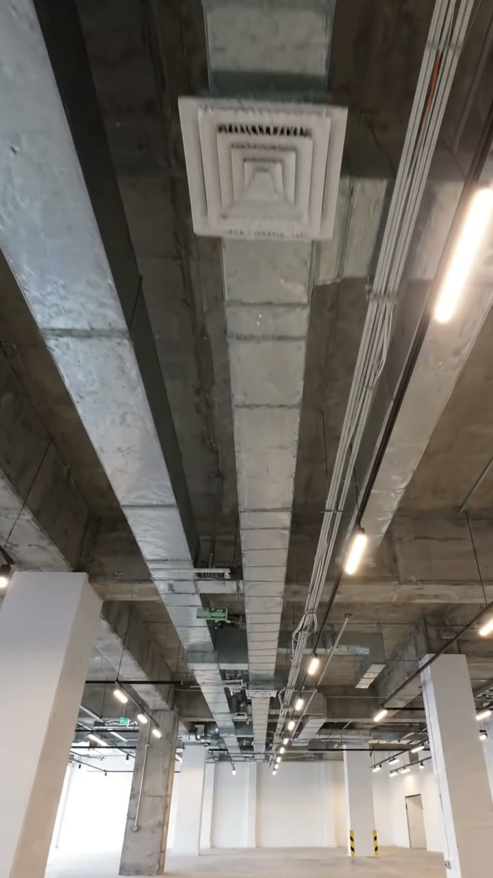 An exposed concrete soffit with ductwork, a diffuser, cable tray and lighting